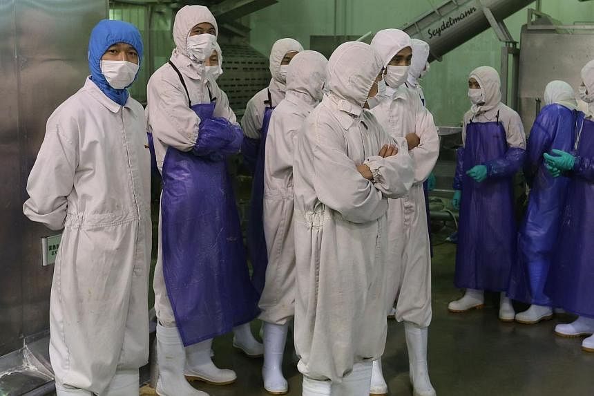 Workers standing aside as inspectors investigate the Shanghai Husi Food Co, a factory of US food provider OSI Group, in Shanghai on July 20, 2014.&nbsp;Chinese police are questioning staff of US food supplier OSI Group for selling expired meat, state
