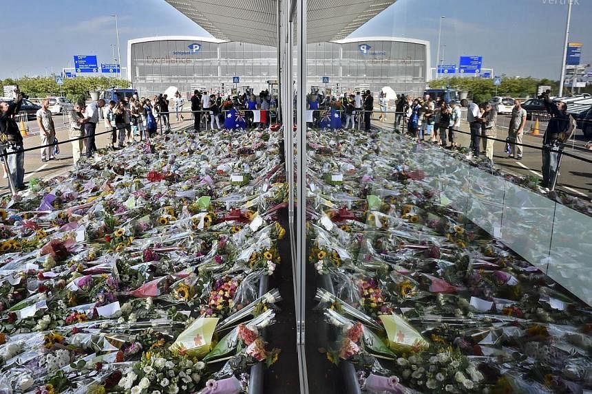 People look at the flowers left in remembrance for the victims of the MH17 plane crash at Schiphol Airport, near Amsterdam, on July 22, 2014. -- PHOTO: AFP