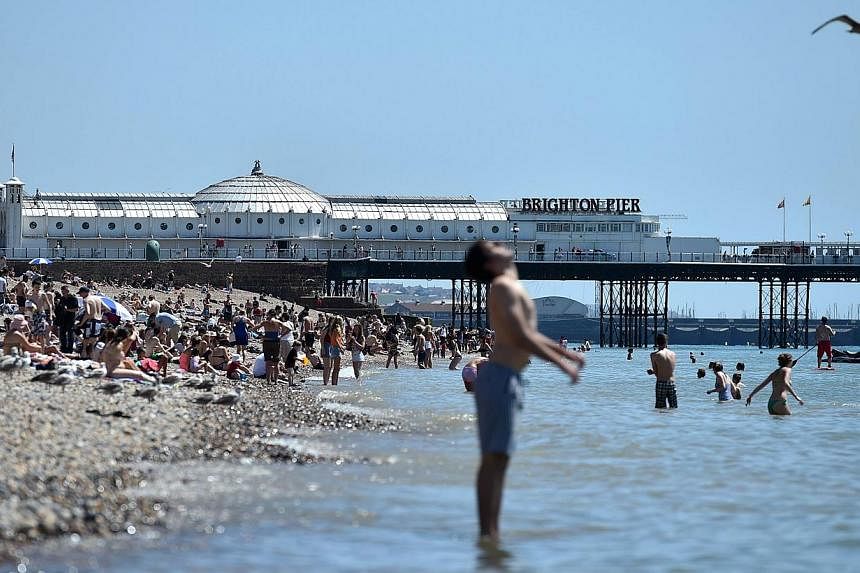 People enjoy the hot weather on Brighton beach in Sussex, southern England, on July 17, 2014. -- PHOTO: AFP&nbsp;