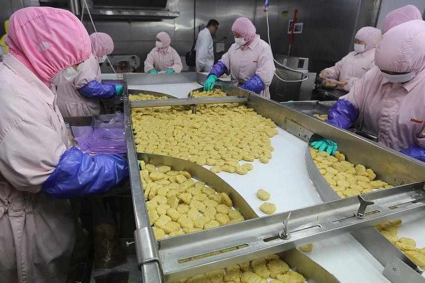 This picture taken on July 20, 2014 shows workers producing food at the Shanghai Husi Food Co, a factory of US food provider OSI Group, in Shanghai. -- PHOTO: AFP&nbsp;