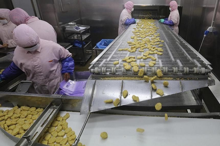 Employees work at a production line prior to a seizure conducted by officers from the Shanghai Food and Drug Administration, at the Husi Food factory in Shanghai, on July 20, 2014. -- PHOTO: REUTERS