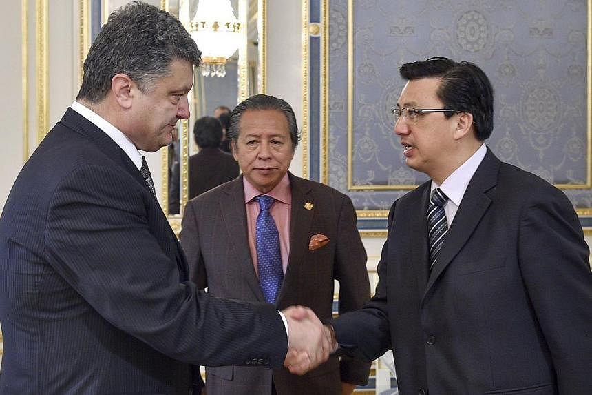 Ukrainian President Petro Poroshenko (left) welcoming Malaysian Foreign Minister Anifah Aman (centre) and Malaysia's transport minister Liow Tiong Lai (right) during their meeting in Kiev on July 21, 2014, prior to talks. -- PHOTO: AFP