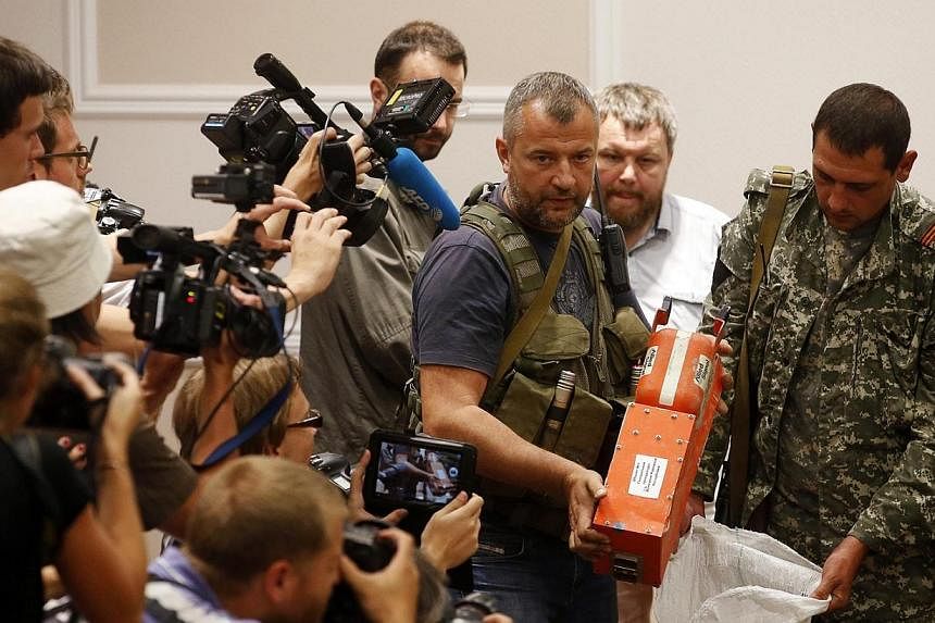 A pro-Russian separatist shows members of the media a black box belonging to Malaysia Airlines flight MH17, before its handover to Malaysian representatives, in Donetsk on July 22, 2014. -- PHOTO: REUTERS