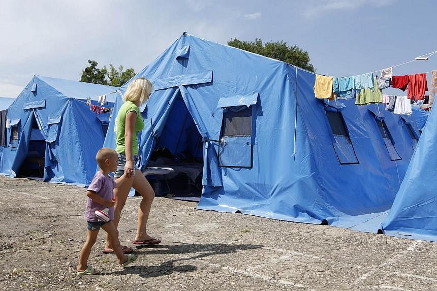 A woman with a child walk at a temporary facility for refugees form Eastern Ukraine, 20 km outside from the Crimean capital Simferopol, on July 17, 2014. Kiev and the West blame Moscow for fuelling the fighting but those leaving the rebels' self-proc