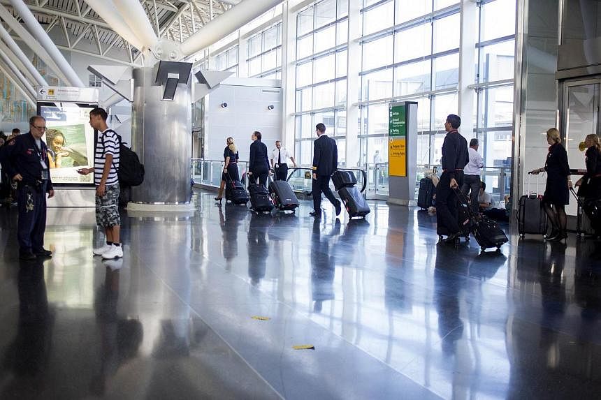People walk in the American Airlines/US Airways Terminal at John F. Kennedy Airport in New York City on July 22, 2014. The Federal Aviation Administration (FAA) has halted all flights from the US to Tel Aviv, Israel following a rocket attack near Ben
