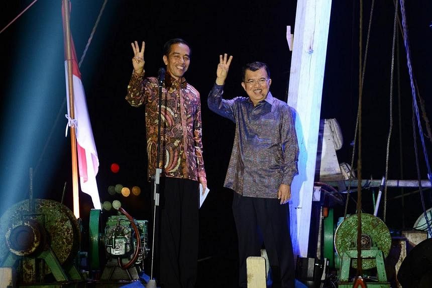 &nbsp;Indonesian presidential candidate Joko Widodo (left) waves with his running mate Jusuf Kalla (right) after delivering his victory address aboard a traditional commercial boat in Jakarta's port district of Sunda Kelapa on July 22, 2014 as the Ge