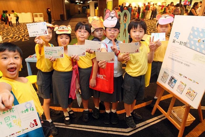 Pupils flashing postcards of their thoughts and wishes for their families at a Lianhe Zaobao exhibition booth on Sep 14, 2013.&nbsp;Registration is open for sharing sessions and workshops at the Mother Tongue Languages (MTL) Symposium to be held on A