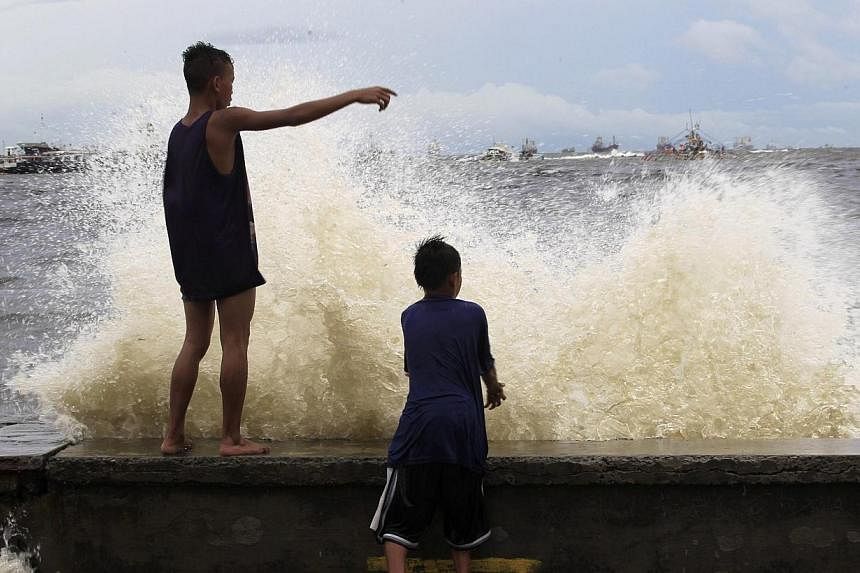 Boys watch waves slamming along a bay brought by Typhoon Matmo, locally named Henry in Navotas city, metro Manila on July 22, 2014.&nbsp;A false tsunami alarm left one person dead and prompted hundreds of others to flee their homes in the Philippines