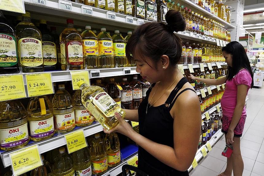 Consumers looking at the healthier cooking oils on display at a Sheng Siong supermarket. Sales of canola oil, soya bean oil and sunflower oil at the supermarket chain rose by 60 per cent last year, compared with that in 2011.