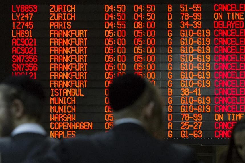 A departure time flight board displays various cancellations as passengers stand nearby at Ben Gurion International airport in Tel Aviv on July 22, 2014. -- PHOTO: REUTERS
