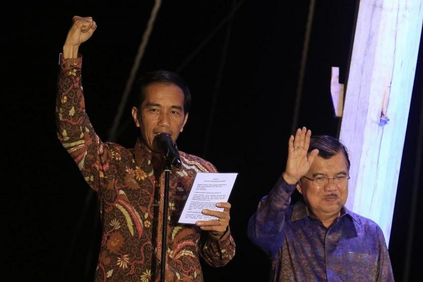 &nbsp;Indonesian presidential candidate Joko Widodo (L) waves with his running mate Jusuf Kalla (R) after delivering his victory address aboard a traditional commercial boat in Jakarta's port district of Sunda Kelapa on July 22, 2014 as the General E
