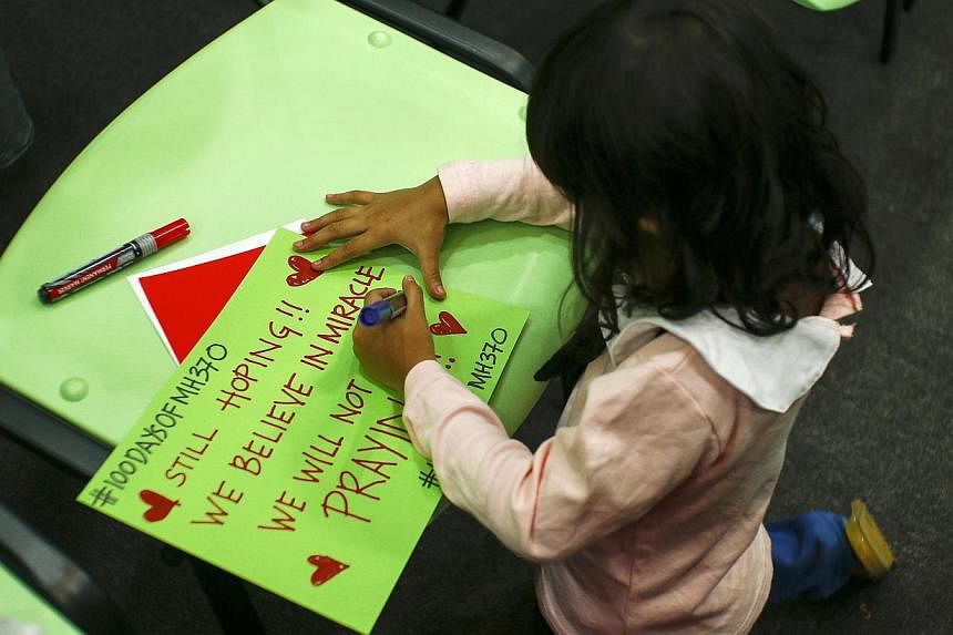 Iman, 4, the daughter of Mohd Hazrin Mohamed Hasnan, one of the crew members on board Malaysia Airlines MH370, writes a message during the 100 Days of Remembrance MH370 event in Kuala Lumpur on June 15, 2014.&nbsp;Australia said the search for missin