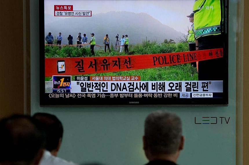 People watch a news broadcast showing coverage of Yoo Byung-Eun, a fugitive business tycoon who was wanted over April's ferry disaster, who was found dead a month earlier in Seoul on July 22, 2014. -- PHOTO: AFP