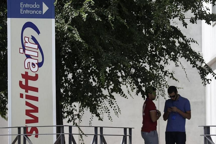Two man stand at the entrance of the headquarters of Spanish private airline company Swiftair, outside Madrid on July 24, 2014. -- PHOTO: REUTERS