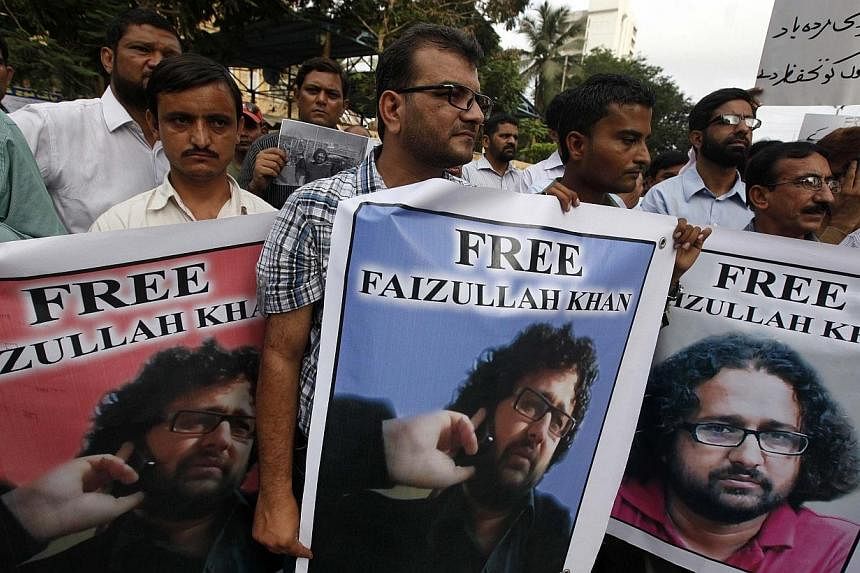 &nbsp;Pakistani journalists carry posters with the picture of local reporter Faizullah Khan, who was detained and imprisoned in Afghanistan, during a protest for his release outside the press club in Karachi on July 15, 2014.&nbsp;Pakistan on Thursda