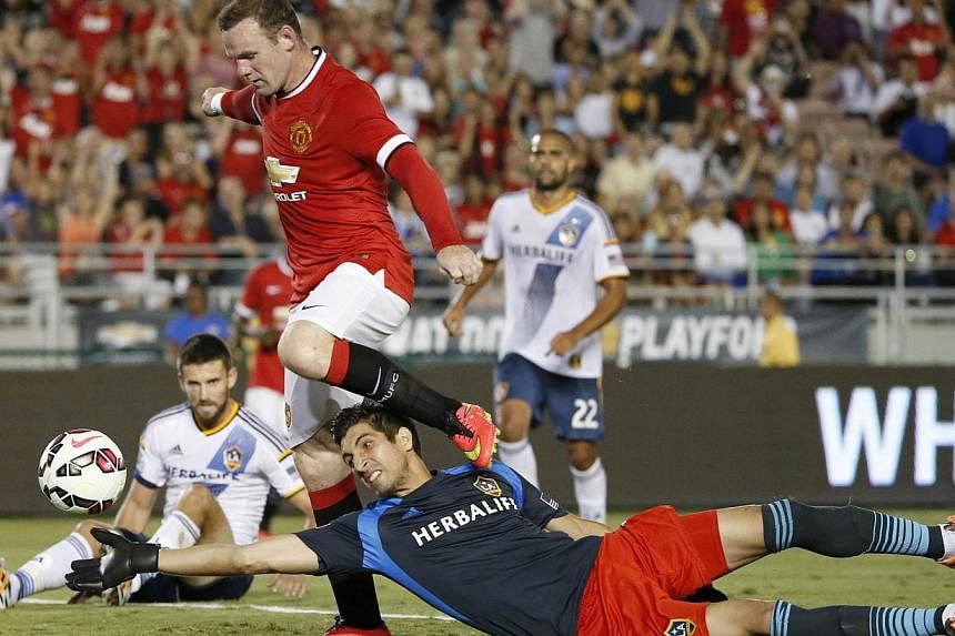 Manchester United forward Wayne Rooney (left) scores past Los Angeles Galaxy's goalkeeper Jaime Penedo during the first half of their international soccer friendly match in Pasadena, California on July 23, 2014. -- PHOTO: REUTERS
