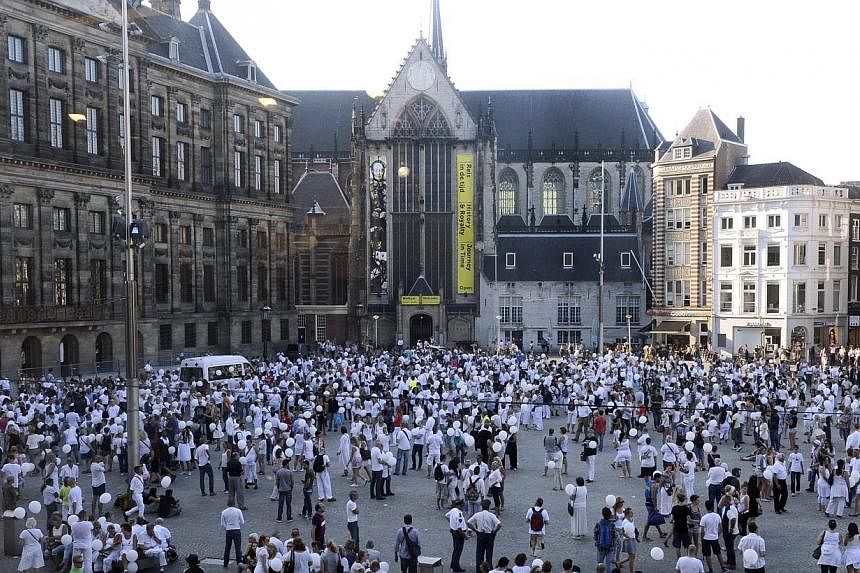 People wearing white clothes gather on Dam Square in Amsterdam, during a silent march in memory of the victims of the downed Malaysia Airlines flight MH17, on July 23, 2014. -- PHOTO: AFP