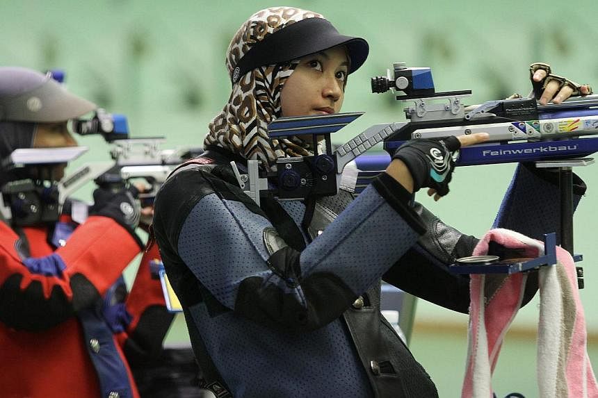 Shooter Nur Ayuni Farhana Abd Halim (right) loading the bullet while competing in Finals 10m Air Rifle Women category during the Tun Tan Siew Sin Trophy 2014 tournament at Subang Shooting Range on July 23, 2014. -- PHOTO: THE STAR/ASIA NEWS NETWORK