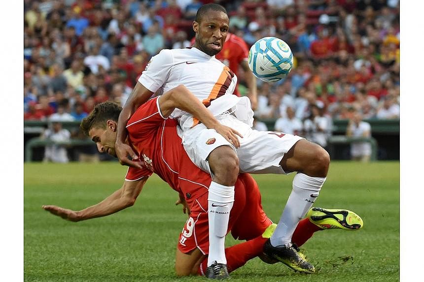 Liverpool's Fabio Borini (left) tussles with Roma's Seydou Keita during a friendly soccer match between Liverpool and Roma at Fenway Park, in Boston, Massachusetts, on July 23, 2014. -- PHOTO: AFP