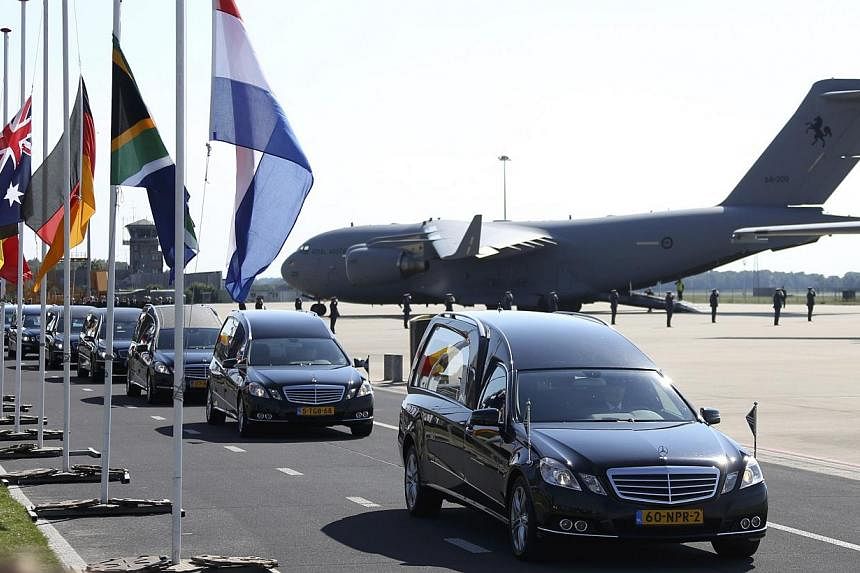 The convoy of hearses with the remains of the victims of Malaysia Airlines MH17 downed over rebel-held territory in eastern Ukraine, drives past international flags as it leaves Eindhoven airport to a military base in Hilversum July 23, 2014. Two air