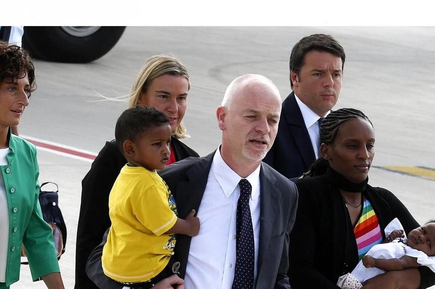 Mariam Yahya Ibrahim of Sudan (right) carries one of her children, as she arrives at Ciampino Airport in Rome with&nbsp;Lapo Pistelli (centre) Italy's&nbsp;vice minister for foreign affairs, holding her other child July 24, 2014. Italian Prime Minist