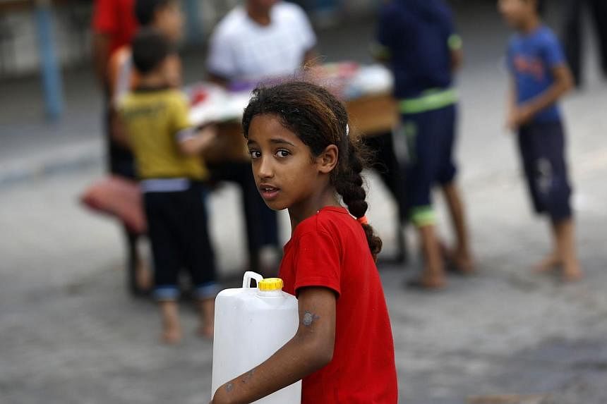 A displaced Palestinian girl carries a fresh water jerrycan at a school used as a shelter in Gaza City on July 18, 2014. -- PHOTO: AFP