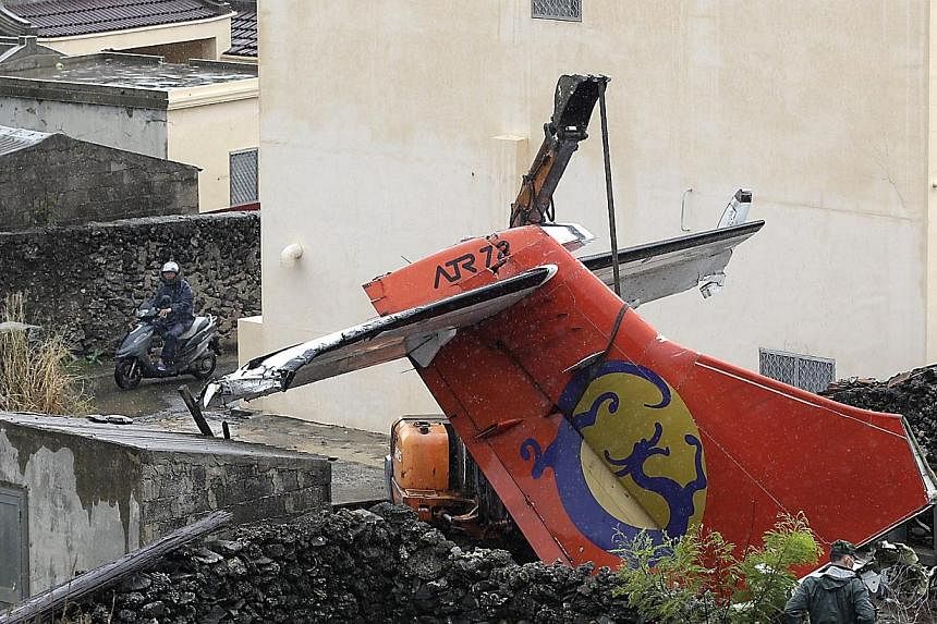 Soldiers remove the wreckage of a TransAsia Airways turboprop plane that crashed on the rooftop, on Taiwan's offshore island Penghu on July 25, 2014.&nbsp;Taiwan's TransAsia Airways ran an apology on the front pages of five major newspapers on Friday