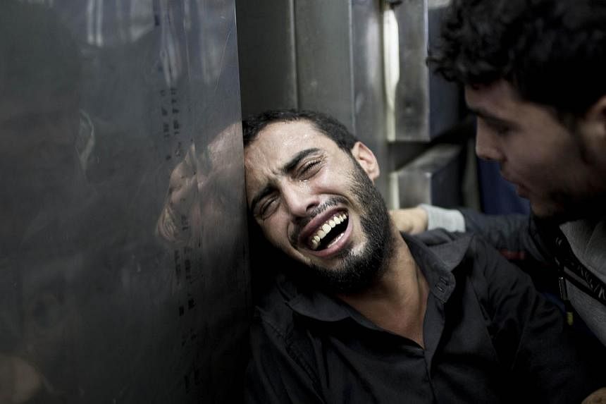 A Palestinian man grieves over the death of his relatives at the morgue of the Kamal Adwan hospital in Beit Lahiya on July 24, 2014, after a UN school in the northern Beit Hanun district of the Gaza Strip was hit by an Israeli shell. -- PHOTO: AFP