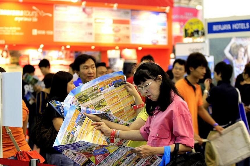 A woman looks through a tour brochure at the Natas Travel 2014 fair held at Singapore Expo in Changi on 1 March 2014. The MH17 plane crash has not deterred Singaporeans from visiting Europe, though some have been checking with travel agents to make s