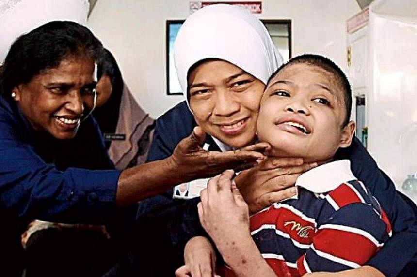 NOW: Nurses K. Malathy and Suria Aziz bidding farewell to Muhammad Firdaus Dullah on Thursday moments before he was taken from the Tuanku Ja'afar Hospital to his new home in Taman Sinar Harapan. -- PHOTO: THE STAR/ASIA NEWS NETWORK