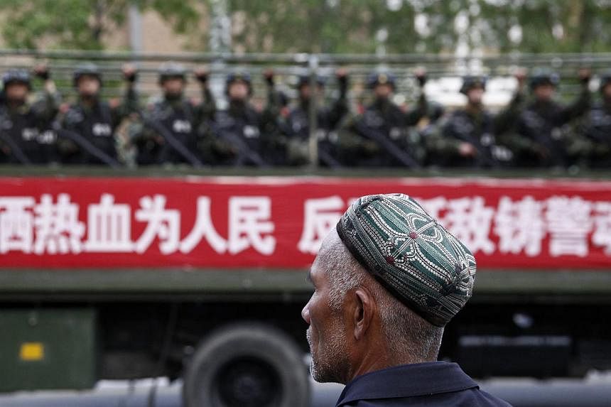 A Uighur man looks on as a truck carrying paramilitary policemen travels along a street during an anti-terrorism oath-taking rally in Urumqi, Xinjiang Uighur Autonomous Region on May 23, 2014.&nbsp;-- PHOTO: REUTERS
