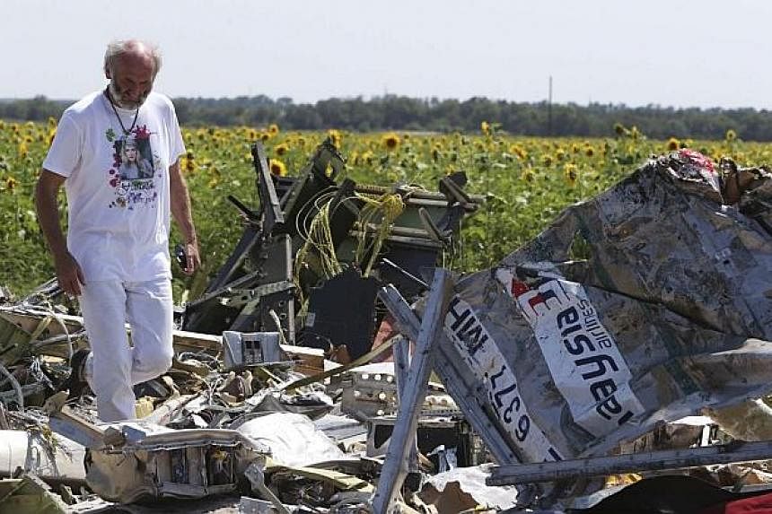 George Dyczynski wears a shirt bearing an image of his daughter Fatima, as he walks through wreckage during his visit to the crash site of the downed Malaysia Airlines Flight MH17. -- PHOTO: REUTERS