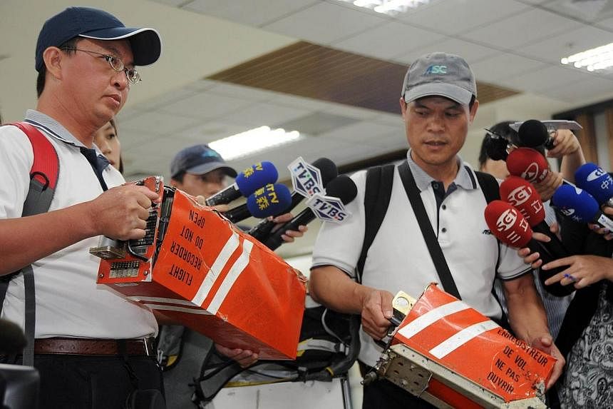 Two members of Aviation Safety Council hold the two black boxes from TransAsia Airways flight GE222 that crashed in the Penghu island chain, in Taipei on July 25, 2014.&nbsp;International experts were examining the site of the fatal TransAsia Airways