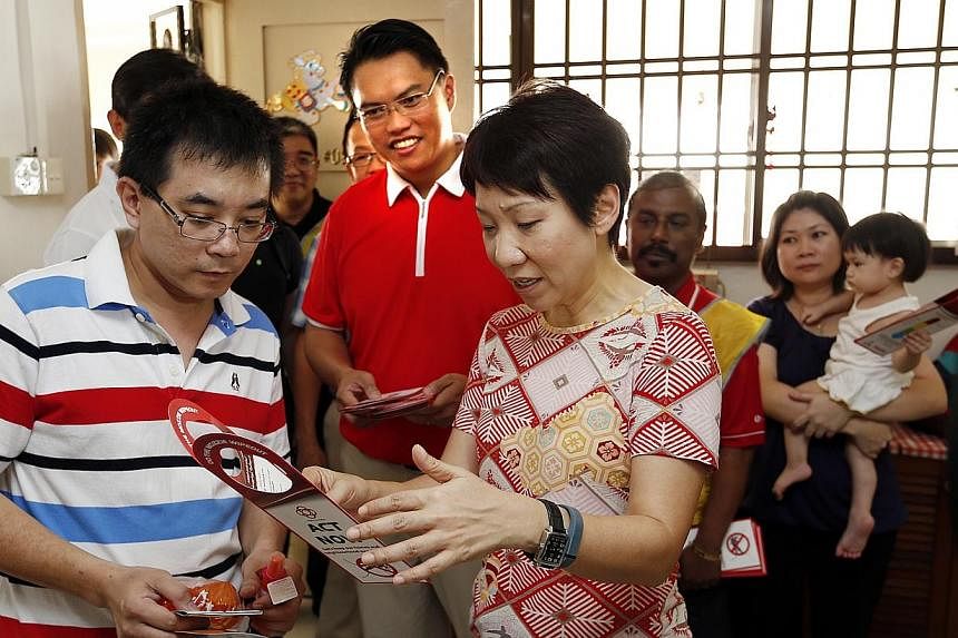 Second Minister for the Environment and Water Resources Grace Fu (front, right) shows&nbsp;Mr Er Kok Hu (front, left) a&nbsp;checklist which comes in the form of a door hanger&nbsp;that includes steps that residents can take to keep their homes and n