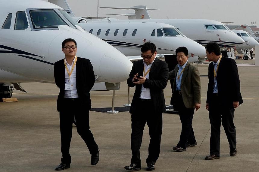 Chinese businessmen walking past private business jets for sale during the Asian Business Aviation Conference and Exhibition at the Shanghai Hongqiao airport. The top one percent of households in Communist-ruled China control more than one third of t