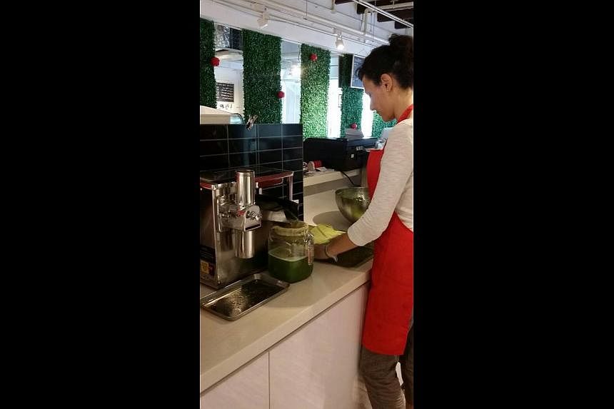 A staff member using a cold-press juicer to make one of the concoctions at Joob in Pickering Street. -- PHOTO: JOOB