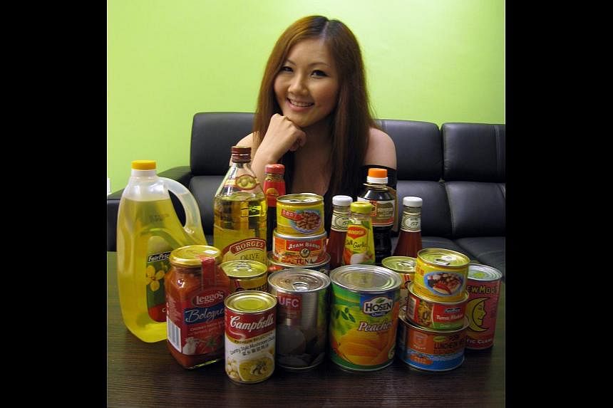 E-commerce manager Luisa Lai (above) with the canned goods, sauces and cooking oil she gets from FairPrice Online. She still visits the supermarket to buy fresh ingredients and will shop online more frequently if the minimum spending for free deliver