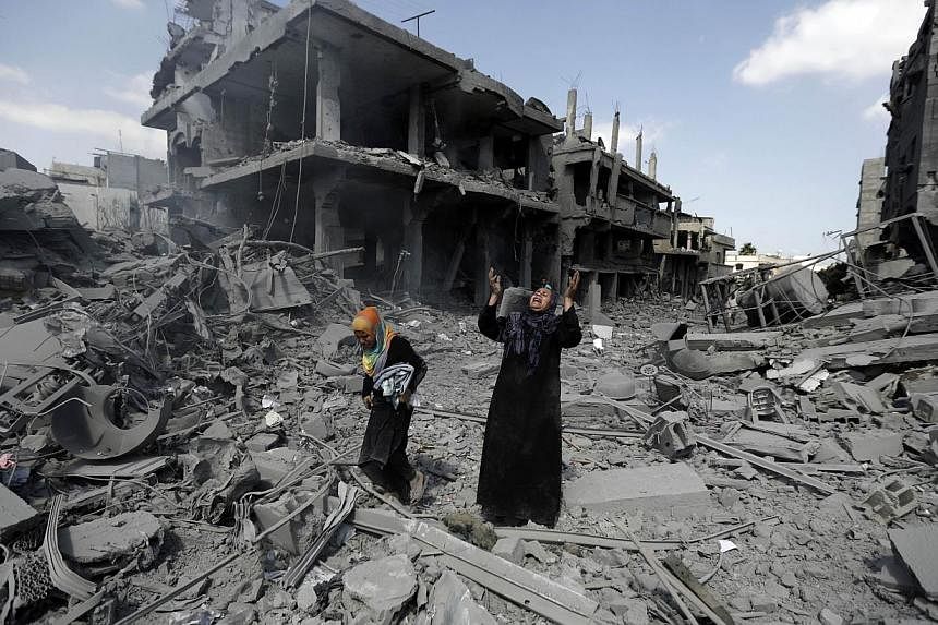 A Palestinian woman pauses amid destroyed buildings in the northern district of Beit Hanun in the Gaza Strip during an humanitarian truce on July 26, 2014. -- PHOTO: AFP