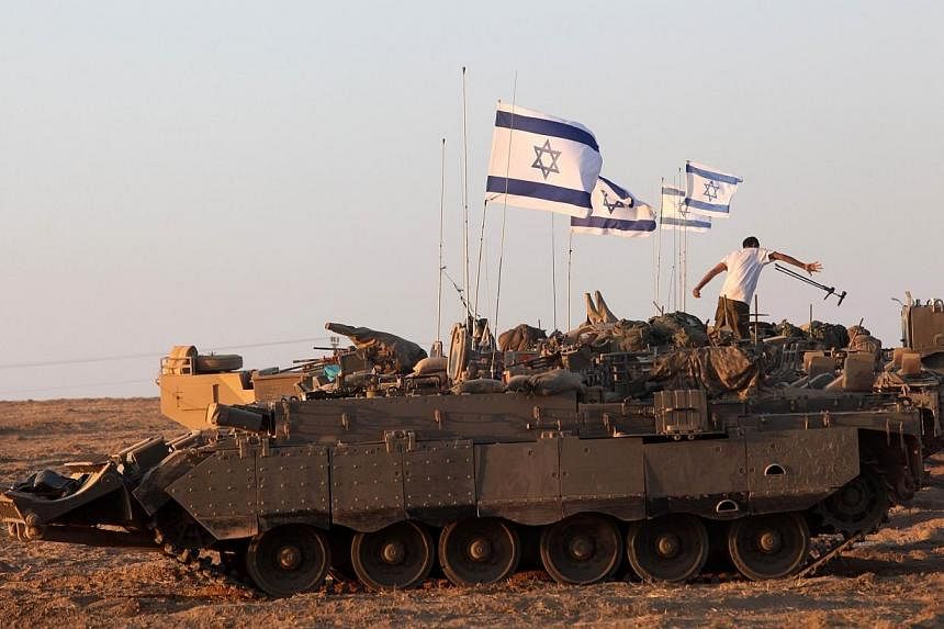 Israeli soldiers work on their an armoured personnel carrier (APC) as they are stationed along the border between Israel and the Hamas-controlled Gaza Strip on July 26, 2014.&nbsp;Israel said on Sunday it was extending a lull in its devastating milit