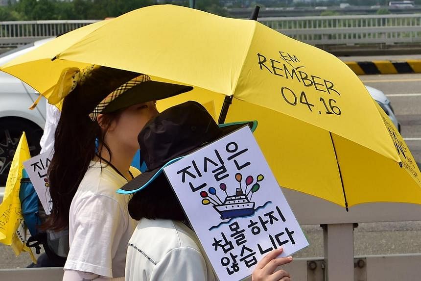A student survivor of South Korea's ferry disaster carries a placard reading "Truth never sinks!" as they march near Parliament in Seoul on July 16, 2014 to press demands by victims' relatives for an independent inquiry into the tragedy that claimed 