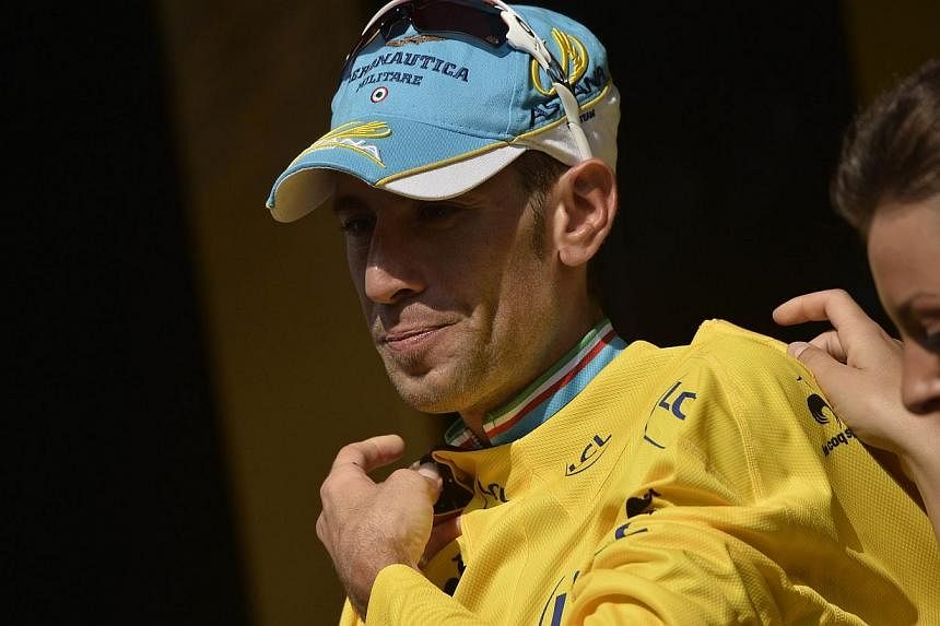 Italy's Vincenzo Nibali celebrates his overall leader yellow jersey on the podium at the end of the twentieth stage, a 54 km individual time trial, as part of the 101st edition of the Tour de France cycling race on July 26, 2014 between Bergerac and 