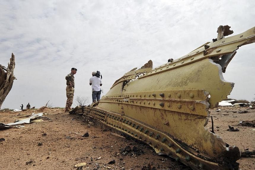 A French soldier and a journalist look at debris of the Air Algerie Flight AH 5017 scattered at the crash site in Mali's Gossi region, west of Gao, on July 26, 2014.&nbsp;French investigators on Sunday, July 27 scoured through the debris of a shatter