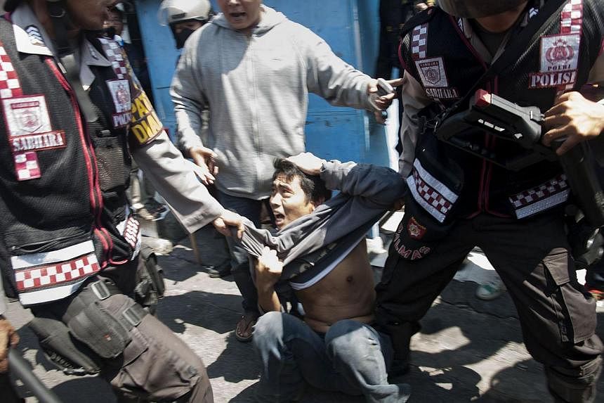 Indonesian police arrest a protester (centre) during a raid by police and military personnel to shut down Surabaya's red light district, popularly known as "Dolly", on the eve of the Eid al-Fitr festival on July 27, 2014.&nbsp;Indonesian police on Su