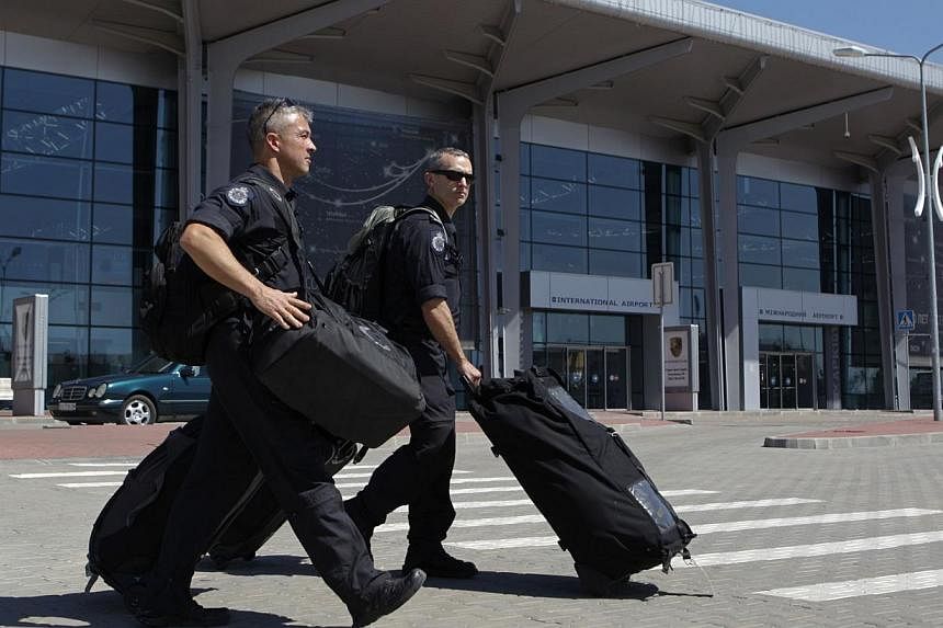 Members of the Australian police mission walk in front of the main terminal after arriving at Kharkiv airport, before proceeding to the crash site of Malaysia Airlines Flight MH17 on July 26, 2014. Australian Prime Minister Tony Abbott said his count