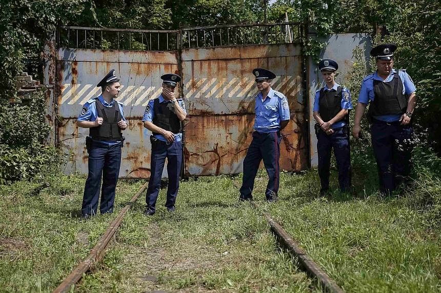 Ukrainian police stand guard at a railway entrance of the Kharkiv tank factory as they wait for a train carrying the remains of the victims of Malaysia Airlines flight MH17, in Kharkiv on July 22, 2014.&nbsp;Sixty-eight Malaysian police personnel wil