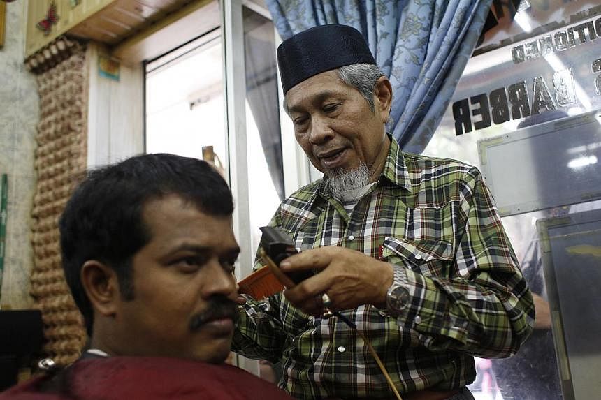 Above: Mr Mahmood Tamam, 63 (right), a long-time resident at Stirling Road, speaking to media representatives during a preview of the My Queenstown Heritage Trail yesterday. Left: Mr Kamsari Gari, 63, trimming the hair of Mr Mohamed Ani, 38, at Jali 
