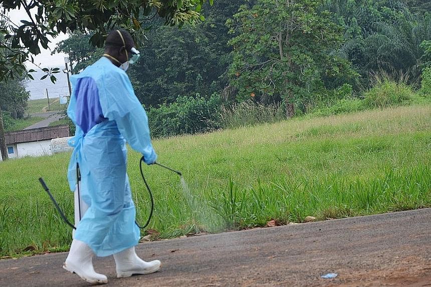 A picture taken on July 24, 2014 shows a staff member of the Christian charity Samaritan's Purse spraying product as he treats the premises outside the ELWA hospital in the Liberian capital Monrovia.&nbsp;The Liberian government on Sunday closed most