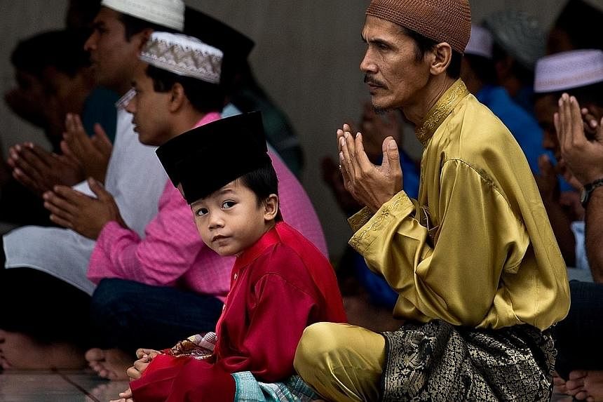 A Malaysian Muslim man offers prayers with his son at the national mosque in Kuala Lumpur on July 28, 2014.&nbsp;-- PHOTO: AFP