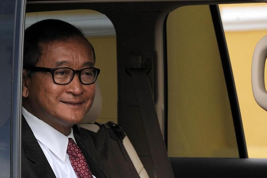 Cambodian opposition leader Sam Rainsy smiles as he sits in a car traveling toward the Royal Palace in Phnom Penh on July 24, 2014.&nbsp;Cambodia's Parliament endorsed opposition leader Sam Rainsy as a lawmaker on Monday as part of a deal with long-t