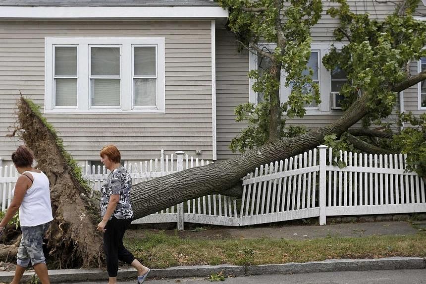 Women walk past a fallen tree after a storm on Wilson Street in Revere, Massachusetts, July 28, 2014.&nbsp;Officials and residents in the Boston-area city of Revere were picking up the pieces early on Tuesday after it was raked by a rare tornado that